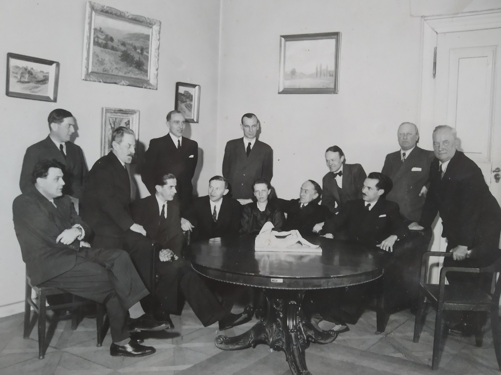 Únor 1942 Ministerstvo školství a národní osvěty, referát pro ochranu přírody a domoviny, foto  u příležitosti 20. výročí činnosti přednosty referátu prof. Rudolfa Maximoviče (20. let založení státní ochrany přírody). Striktně vzato, oficiálně působil RM jako zaměstnanec na ministerstvu od března 1922, ale prof. Wirth jej jmenoval expertem a konzervátorem s pověřením od ministerstva úkoly ochrany přírody při provádění pozemkové reformy již od 1919. Zleva: sedící Dr. Volek, stojící  doc. Dr. Mencl, prof. R. Maximovič, stojící dr. Kousal, tajemník Krček, sedící kolem stolu zleva prof. Vlk, dr. Sýkora, vrch. kanc.ofic. Doležalová, dr. Slepička, prof. Vašíček, prof. Linek, stojící u dveří dr. Hlávka, dr. Kolařík. Foto archiv Zdeňky Stejskalové a Vojtěcha Stejskala